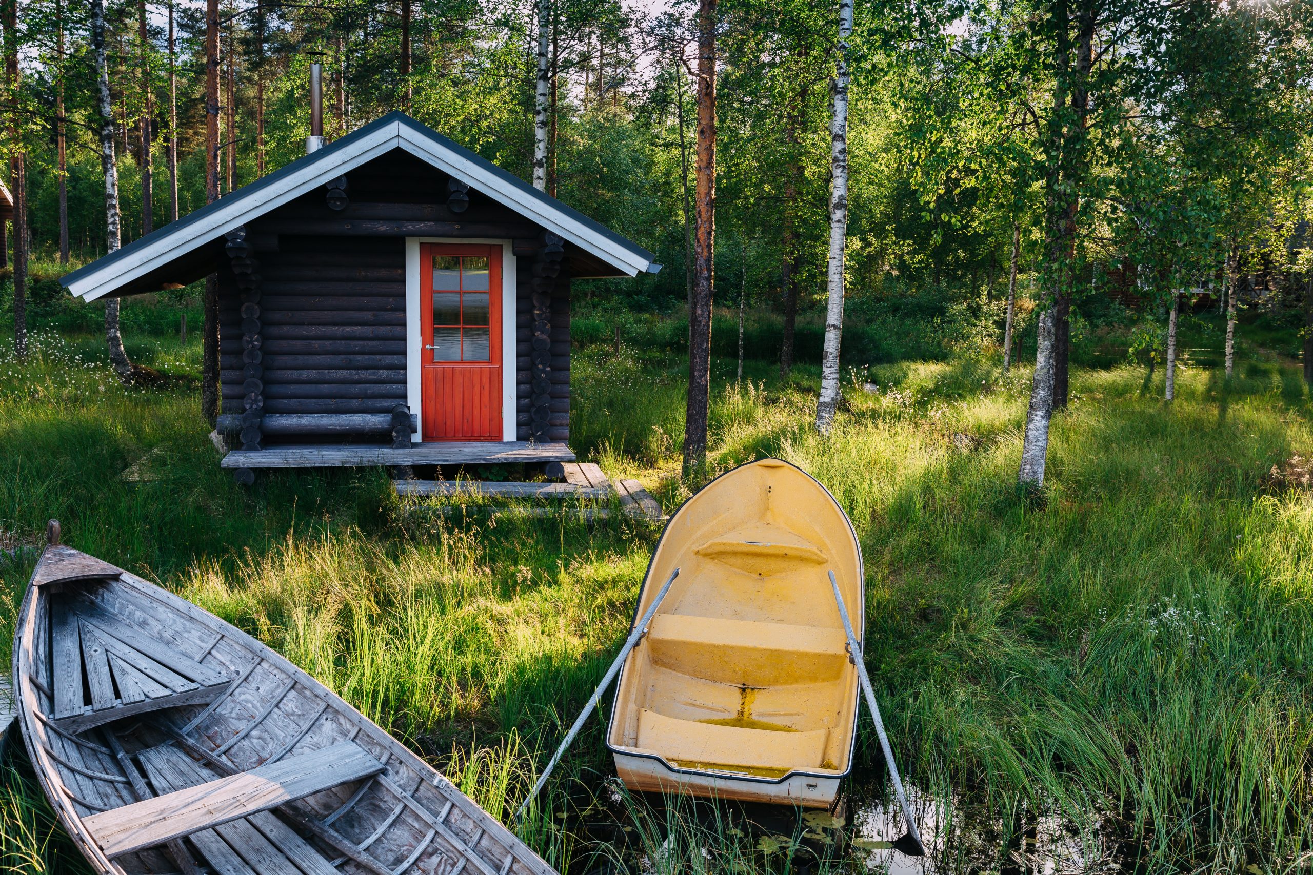 Traditional wooden hut. Finnish sauna on the lake and pier with fishing boats